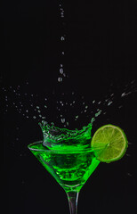 Fototapeta na wymiar Green drink in a glass. Green water or limnad. A splash of green liquid similar to absinthe. Alcohol and alcoholism.