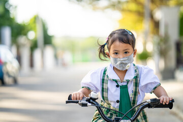 Obraz premium Girl riding bicycle wearing healthy face mask to prevent virus and PM2.5 pollutions 