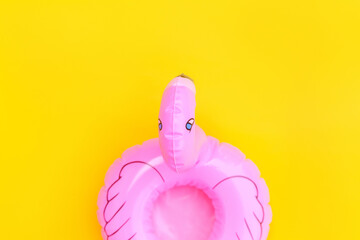 Summer beach composition. Simply minimal design with pink Inflatable flamingo isolated on yellow background. Pool float party, trendy celebrity fashion concept. Flat lay top view copy space.