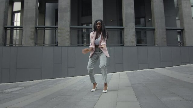 Beautiful Black Girl Dancing On The Street. Behind Her Tall Buildings. Modern Dances.