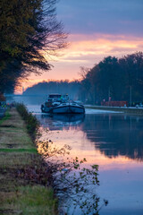 Fototapeta premium Cargo ship on a river during a misty sunrise morning. High quality photo