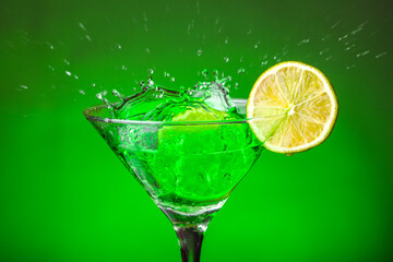 Green drink in a glass. Green water or limnad. A splash of green liquid similar to absinthe. Alcohol and alcoholism.