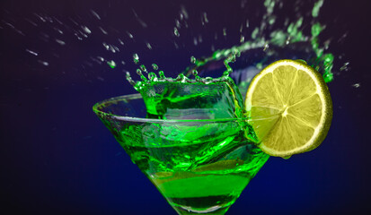 Green drink in a glass. Green water or limnad. A splash of green liquid similar to absinthe. Alcohol and alcoholism.