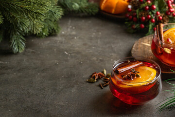  Mulled wine  glass decorated with cinnamon and anise on concrete background with Christmas decration. Winter time beverage  concept. Copy space.