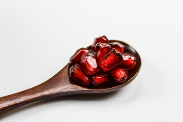 Close up. Macro. A wooden spoon with seeds in it. Wooden spoon with pomegranate seeds isolated on a white background. Fruit pomegranate. The concept of healthy eating.