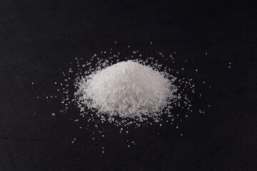 Obraz na płótnie Canvas Glutamic acid monosodium salt on a dark background. Pile Msg or Food additive E621. Selective focus, copy space. Flavor seasoning for enhancing food impressions. The additive is used in food industry
