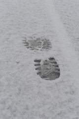 Shoe footprints and traices in white fresh snow on a snowy path and trail in winter