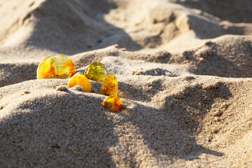 Amber on a sandy beach. A group of pieces of transparent mineral Sunstone on a background of sand. Ancient resin. Semi-precious stones
