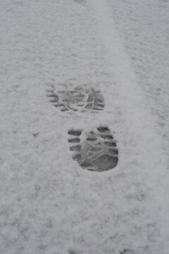 Shoe footprints and traices in white fresh snow on a snowy path and trail in winter