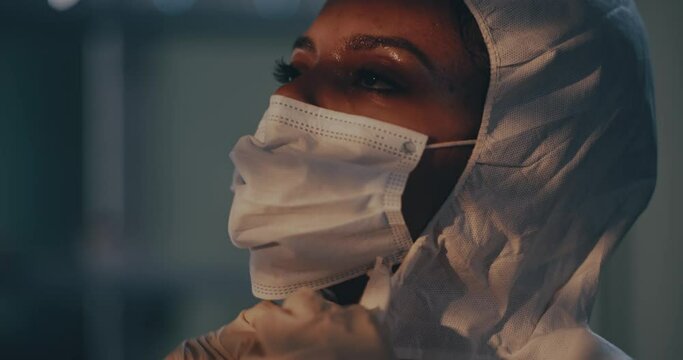 Sweaty black woman taking of hazmat suit