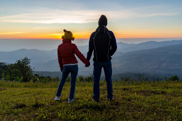 Young couple traveler looking at the sunrise over the mountain