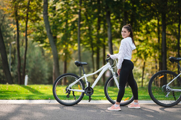 Beautiful girl posing at white bicycle. Walk in nature.