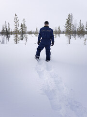 Fototapeta na wymiar A man from behind in snow overalls on the Lapland tundra on virgin snow