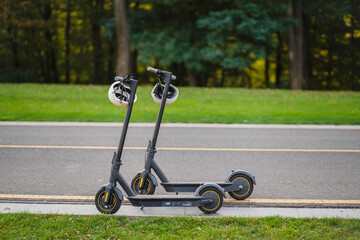 two electric kick scooters or e-scooter parked on the sidelines road