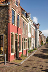 Fototapeta na wymiar Delft, The Netherlands, November 11, 2020: row of traditional facades with brick and plaster along Rietveld canal in the old town