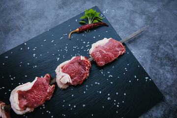 Raw and fresh beef meat steaks on the black background.