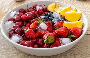 Bowl of colourful fruit strawberries black berries peach and cherries