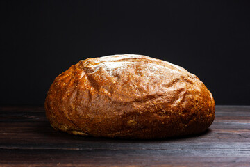 Round black bread on a dark wooden table. Rustic style. Freshly baked black bread.