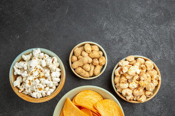 Obraz na płótnie Canvas top view tasty cheese cips with different snacks on dark background movie cinema photo potato nut junk food