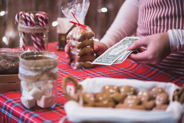 Christmas, New Year pastry shop. Woman waitress counting us dollars selling gingerbread cookies, sweets, marshmallow in a small cozy cafe.