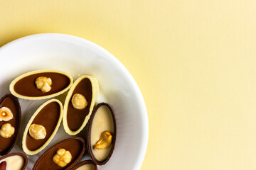 Chocolates on a white dish. Black and white chocolate with nuts