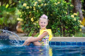 Fototapeta premium Little girl playing and spraying water in swimming pool outdoors at summer. Summer vacation concept