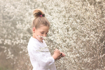 Spring portrait of beautiful young girl with blooming trees background. Spring time nature concept.