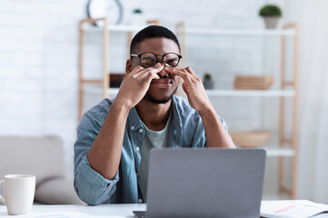 African Man Massaging Eyes After Work On Computer At Workplace