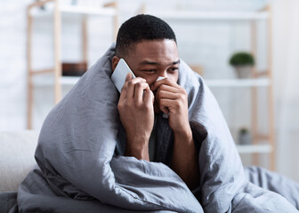 Ill Black Man Calling Doctor Having Runny Nose Sitting Indoors