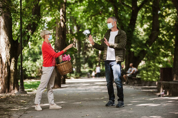 Senior people together in times of coronavirus social distancing in the park. New normal.