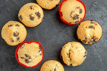 Close up view of freshly baked small cupcakes with chocolates on dark background