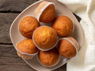 There is a plate of biscuit muffin on the wooden table. Delicious homemade cakes top view.