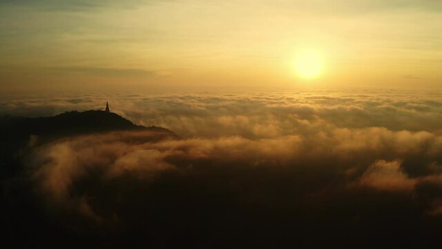 Beautiful golden sunrise sky above fluffy cloudy with antique Buddhism stupa on mountain peak, dramatic light in twilight sky. Aerial view from drone.