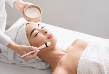 Attractive young asian woman receiving skin treatment at spa center