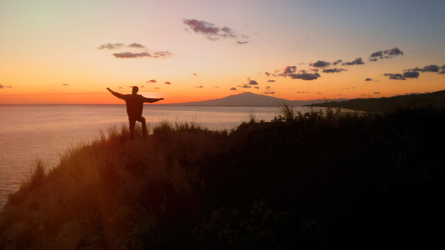 Silhouette di un ragazzo con le braccia in aria al tramonto 