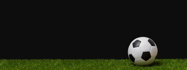 Soccer football ball on green grass over black background