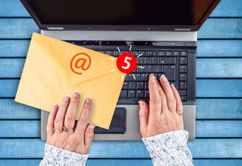 woman hands holds envelope with new mail notification icon and at sign and laptop
