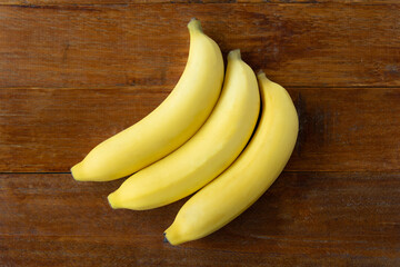 Fresh yellow bananas for healthy breakfast in wood plank background