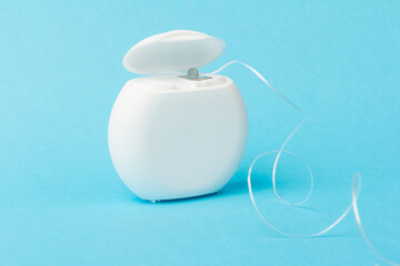 Dental floss container on blue background. Daily oral hygiene, teeth care and health. Cleaning products for your mouth, copy space. Dental care concept.
