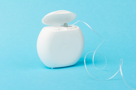 Dental floss container on blue background. Daily oral hygiene, teeth care and health. Cleaning products for your mouth, copy space. Dental care concept.