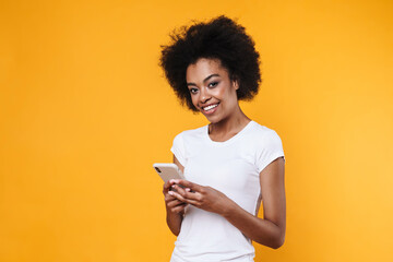 Happy young african american woman smiling and holding cellphone