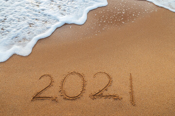 Happy New Year 2021 concept, lettering on the beach. Written text on the sea beach at sunrise.