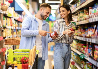 Happy millennial couple with the cart shopping in supermarket