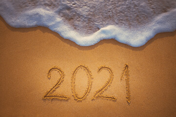 Happy New Year 2021 concept, lettering on the beach. Written text on the sea beach at sunrise.