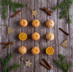 Orange mandarines with branches Christmas tree and cinnamon on wooden background