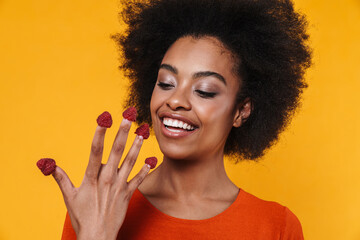 Smiling african american girl making fun with raspberries