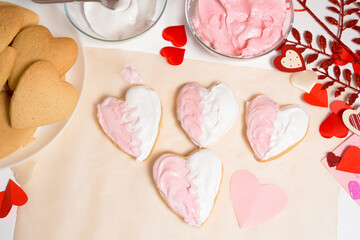 Fototapeta na wymiar cookie heart decorated with glaze white and pink for Valentine's day, close-up, baking for the holiday. decorative hearts top view