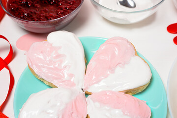 cookie heart decorated with glaze white and pink for Valentine's day, close-up, baking for the holiday. decorative hearts top view