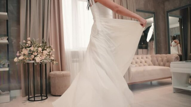 Young beautiful woman demonstrates white wedding dress during photo shoot in studio.