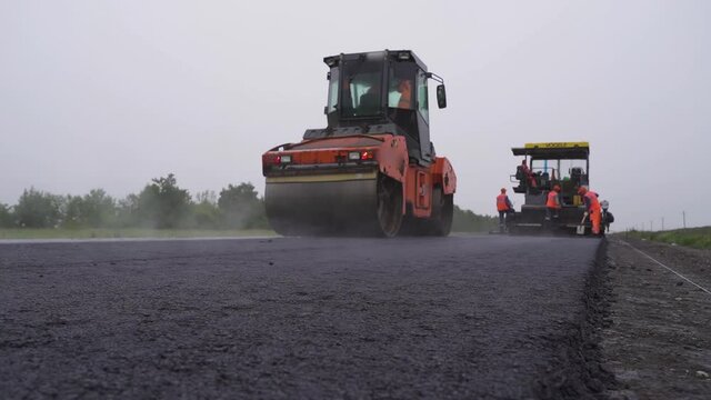 An asphalt concrete roller compresses hot asphalt. evaporation, steam